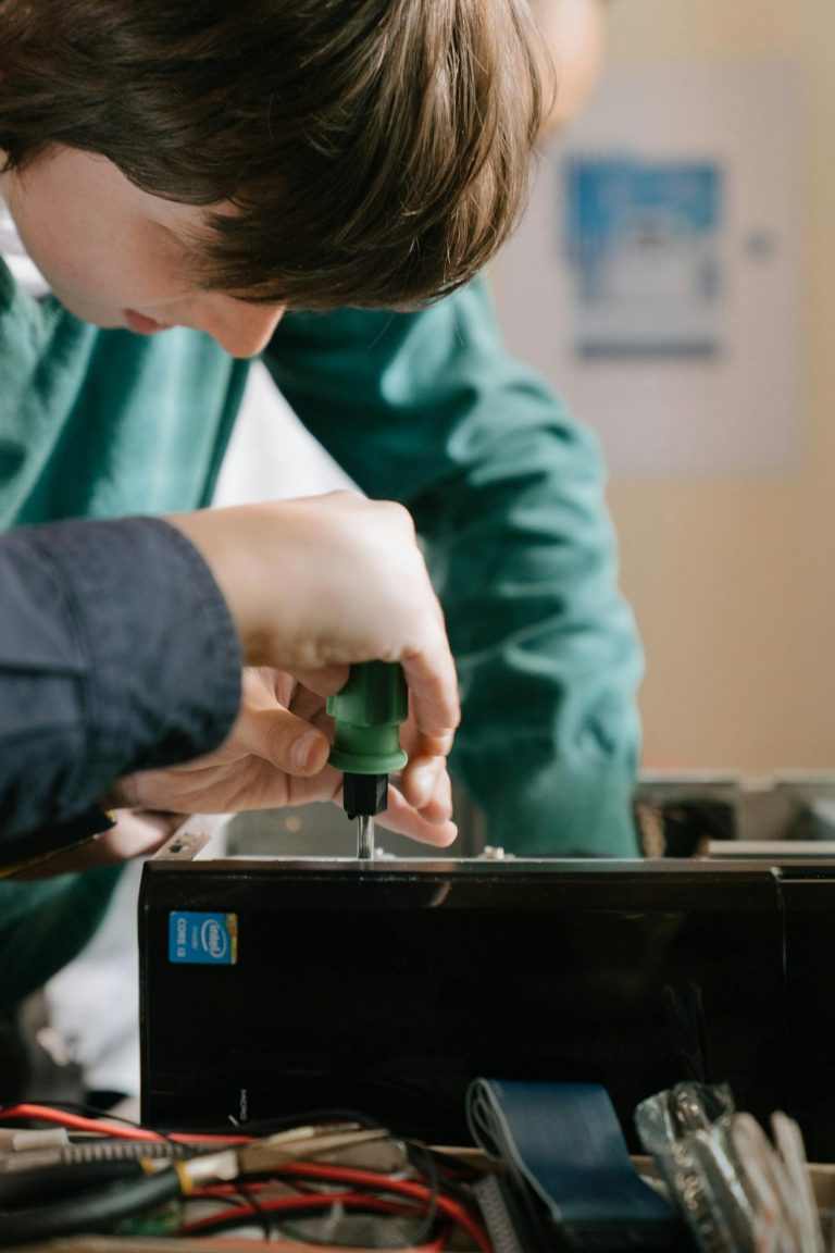 Close-up of hands repairing a computer with a screwdriver inside.