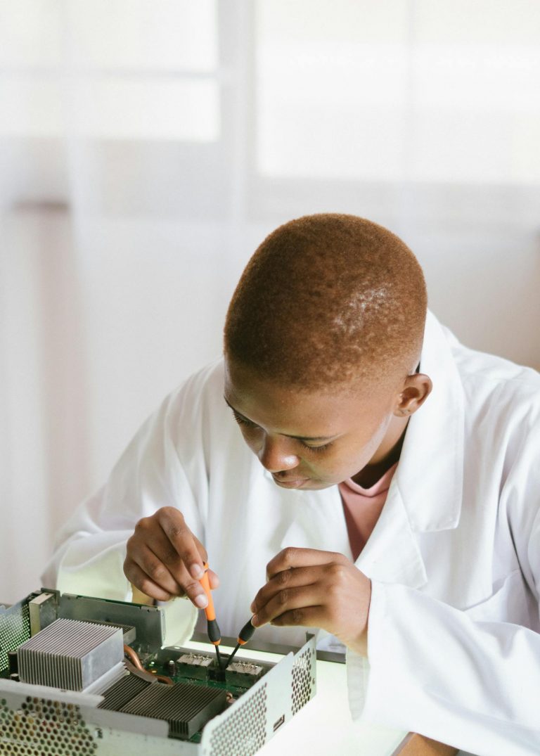 Young technician focusing on electronics repair at a desk indoors.